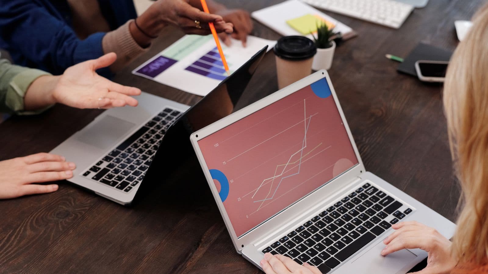 Colleagues reviewing performance charts on two laptops across a meeting table, illustrating measurement of corporate retreat ROI