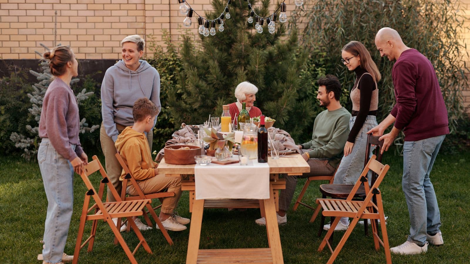 Multi-generation family sharing a meal at a long backyard table