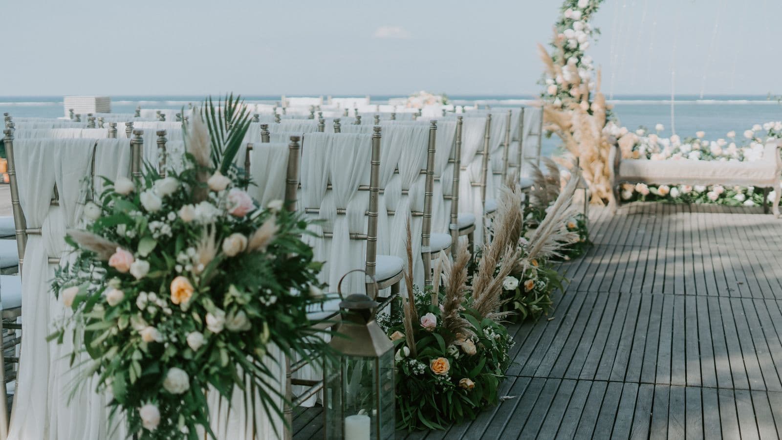 Rows of white-draped ceremony chairs on an oceanfront wedding deck