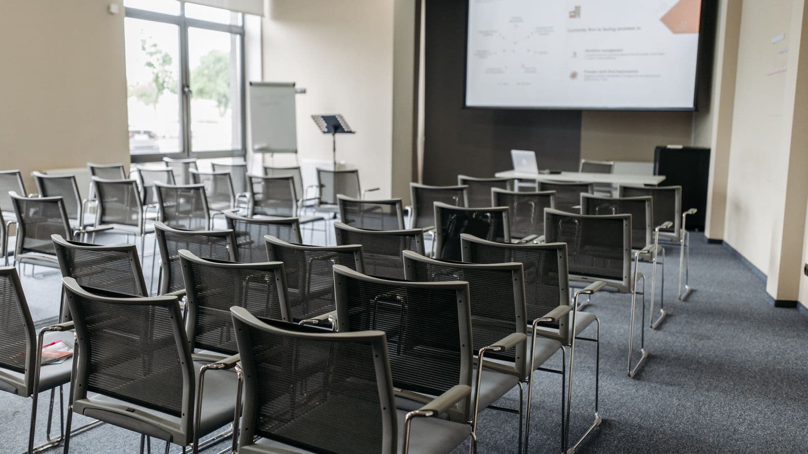 Empty hotel conference room with rows of chairs facing a blank screen, suggesting a corporate retreat that missed the mark