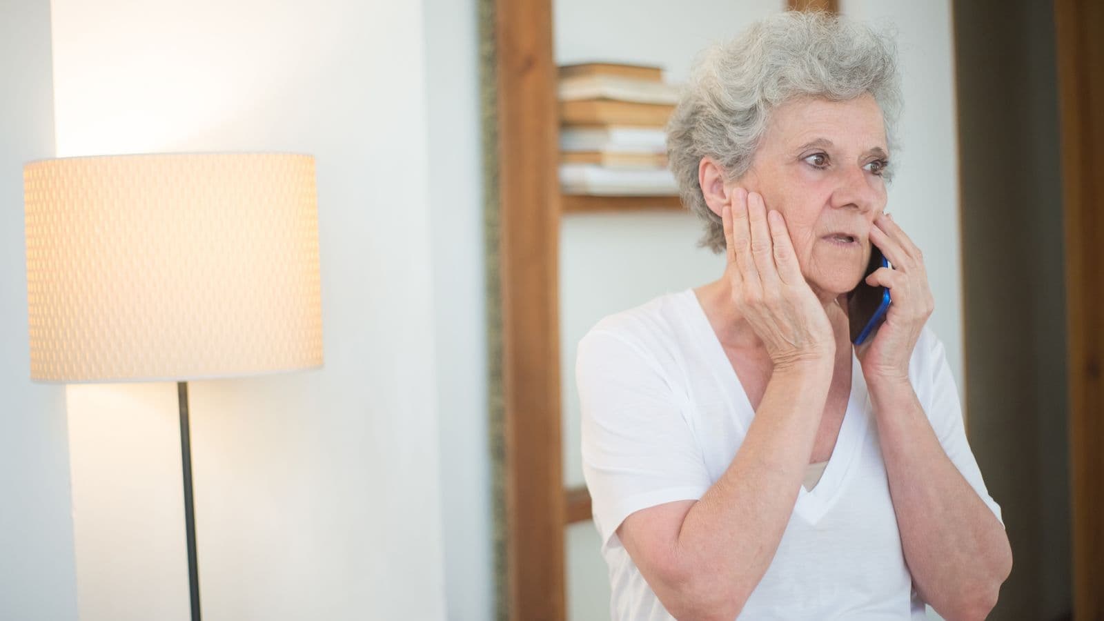 An older woman listening carefully on a phone call at home