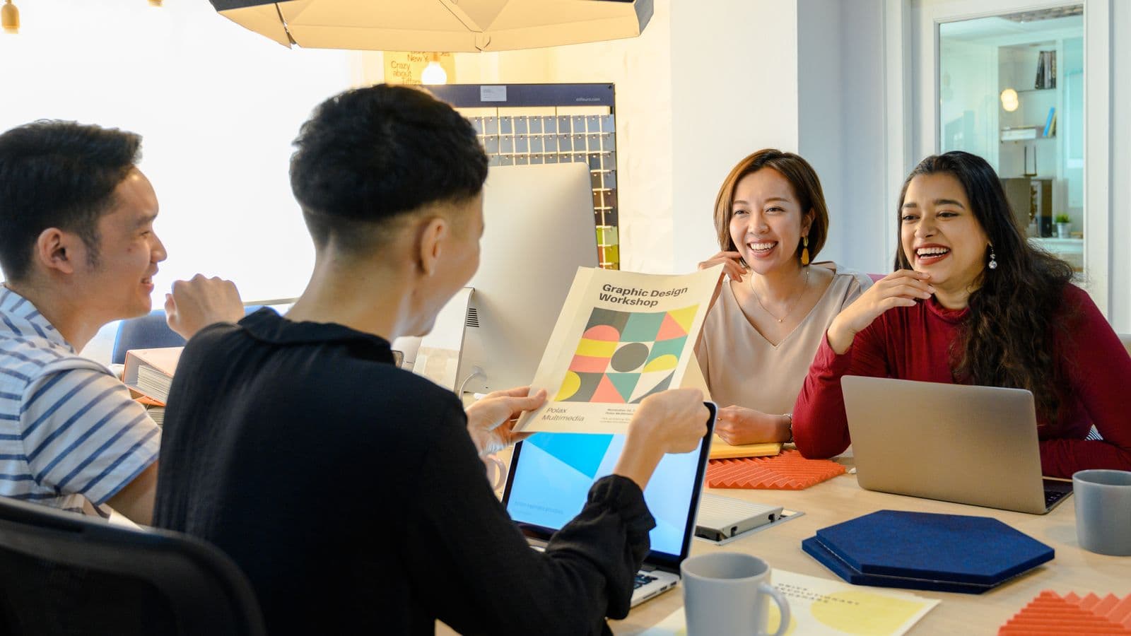 Colleagues laughing together around a table during a working session