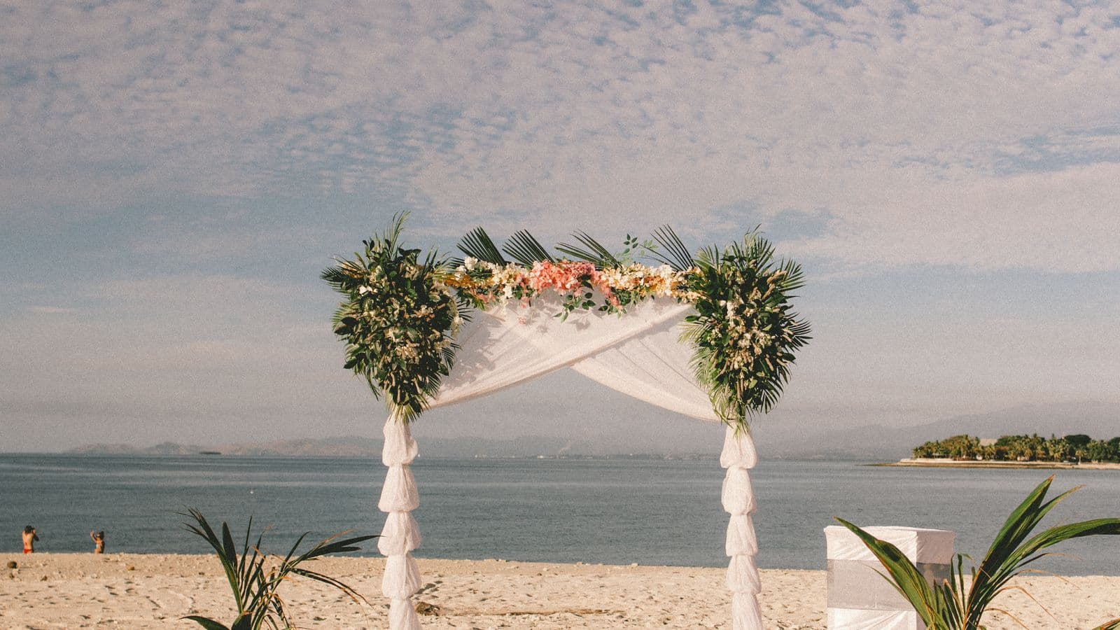 Wedding arch set up on a sandy beach framed by the ocean