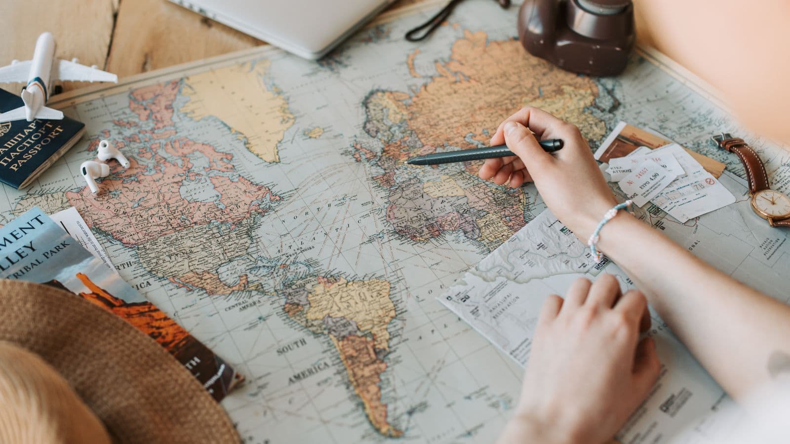 Traveler planning a trip with a world map, passport, and tickets