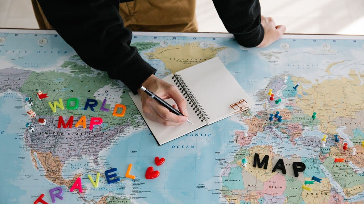 Person planning a trip in a notebook over a world map