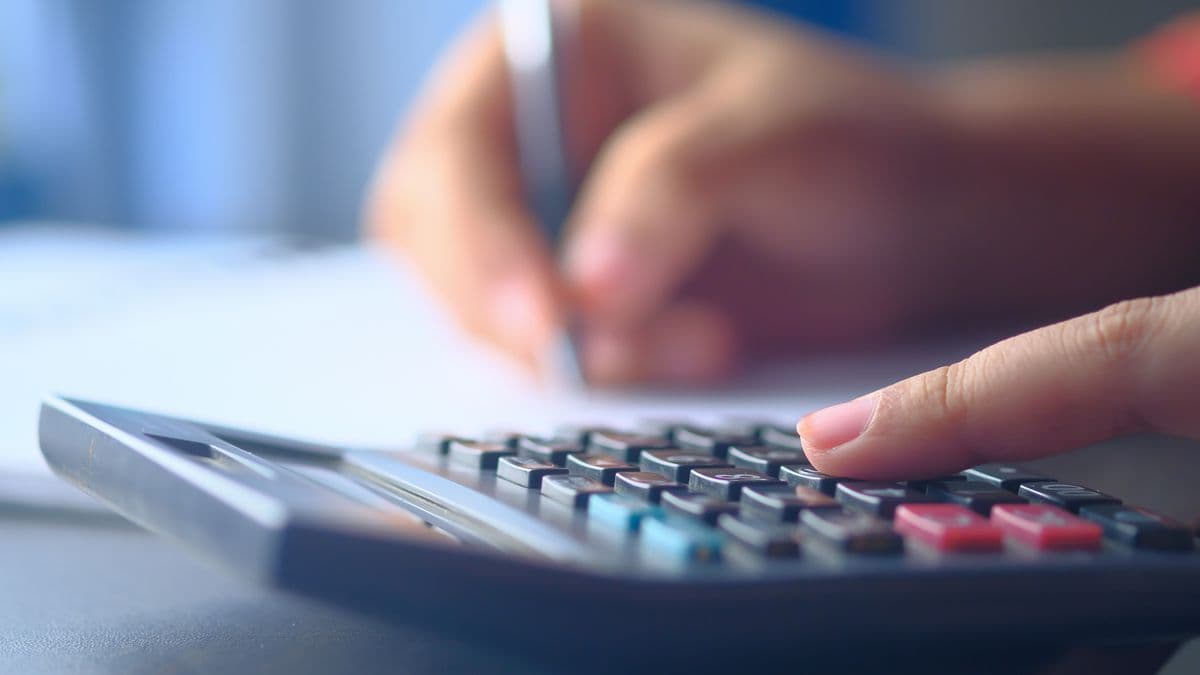 Hands working through numbers with a calculator and notepad