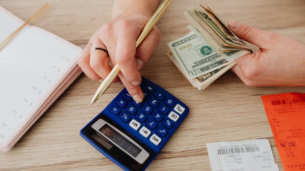 Hands counting cash over a calculator and receipts